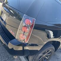 Black GMC SUV rear quarter with a dented, creased panel beside the tail light
