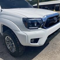 The same white Toyota Tacoma front with the bumper and fender straight and smoked headlights